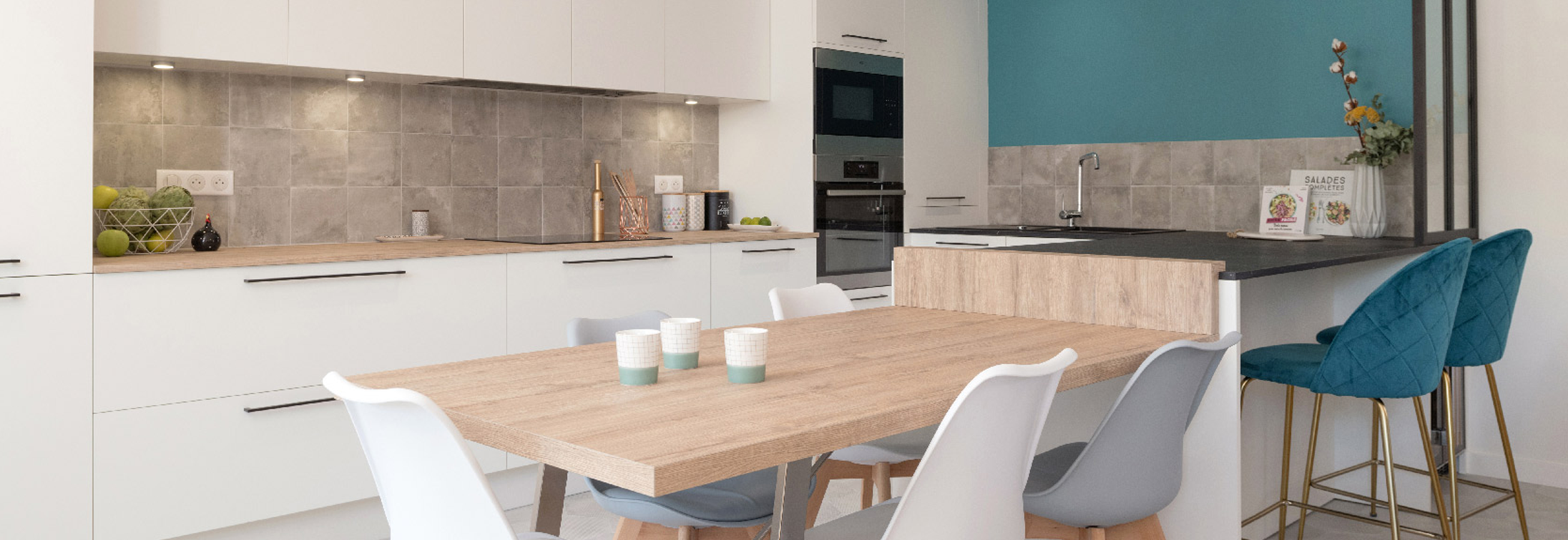 Publication dans le journal de la maison. La réalisation de Skéa Designer "Au Bleu de toi" est mise en avant dans la presse. La cuisine blanche et bois avec sa table et son îlot se tiennent devant un mur bleu.