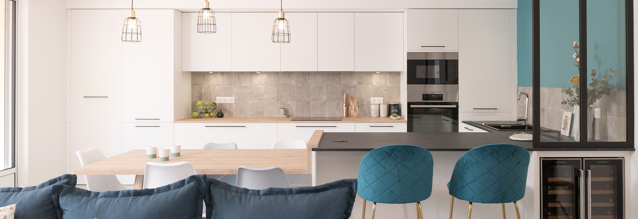Publication dans le magazine Maison et travaux. La réalisation "Au Bleu de toi" est mise en avant. Ici la cuisine avec son îlot qui se prolonge en table, ses façades blanches, ses fauteuils bleus.